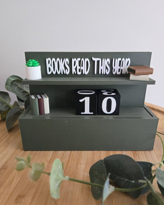 Decorative bookshelf with 'Books Read This Year' display on a wooden surface with plants.